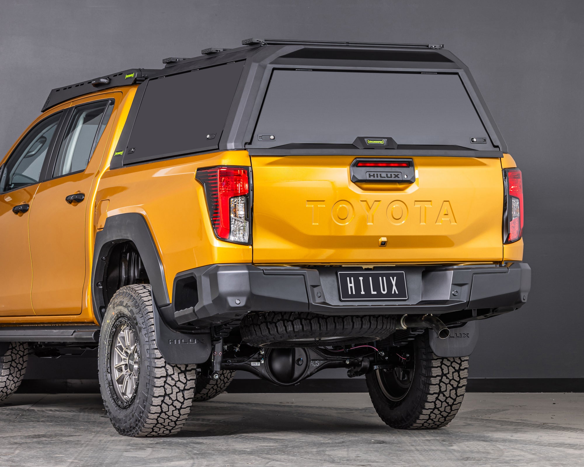 toyota-hilux-n90-2026-sunglow-orange-with-ironman-4x4-raid-canopy-tradie-pack-rear-three-quarter-angle